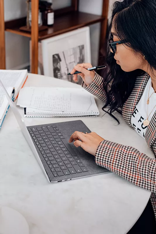 woman on a labtop reading a paper